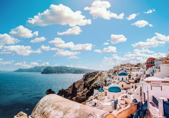 Hillside of Greece with the ocean and buildings, blue sky with clouds
