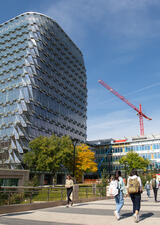 Students walk past the LEED-certified Mackimmie Tower. A crane is visible in background.